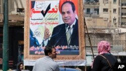 People walk past a banner supporting proposed amendments to the Egyptian constitution on new term limits, with a poster of Egyptian President Abdel-Fattah el-Sissi in Cairo, Egypt, April 16, 2019.