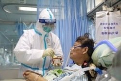 A nurse in a protective suit feeds a novel coronavirus patient inside an isolated ward at Zhongnan Hospital of Wuhan University, during the Lantern Festival, in Wuhan, Hubei province, China, Feb. 8, 2020.