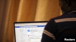 FILE - A man opens the Facebook page on his computer to fact check coronavirus disease (COVID-19) information, in Abuja, Nigeria, March 19, 2020