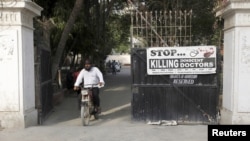 A man rides on a motorbike past a poster installed at the entrance gate of the Pakistan Medical Association office in Karachi, April 8, 2015.