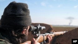 FILE- A militant fighter aims a sniper rifle during fighting in Tal Tamr, Hassakeh province, Syria, in this image posted by the Al-Baraka division of the Islamic State group, Feb. 24, 2015.