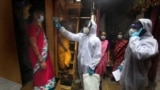 A health worker checks the body temperature of a resident, as others await their turn during a free medical checkup in a slum in Mumbai, India, Sunday, June 28, 2020. India is the fourth hardest-hit country by the COVID-19 pandemic in the world…