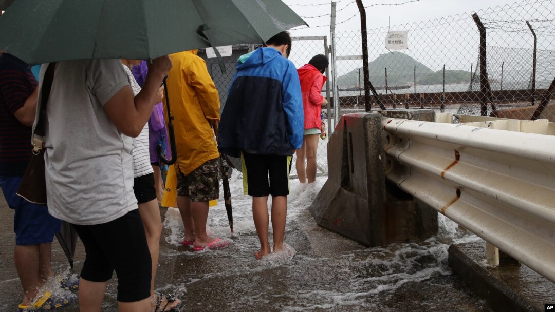 Orang-orang bermain air yang disebabkan oleo Topan Nida di Hongkong Selasa (2/8).