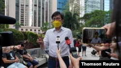 FILE - Pro-democracy activist Avery Ng gestures to the media before a trial over charges related to an unauthorized assembly on Oct. 1, 2019, outside the court in Hong Kong, May 17, 2021.