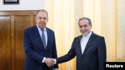 Menteri Luar Negeri Rusia Sergei Lavrov berjabat tangan dengan Menteri Luar Negeri Iran Abbas Araqchi selama pertemuan di Teheran, Iran, 25 Februari 2025. (Kementerian Luar Negeri Rusia/Handout via REUTERS)