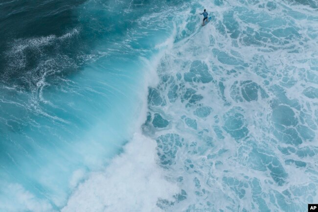 A surfer rides a wave in Teahupo'o, Tahiti, French Polynesia, Saturday, Jan. 13, 2024. The world-famous surf spot is set to host the 2024 Paris Olympics surfing competition. (AP Photo/Daniel Cole)