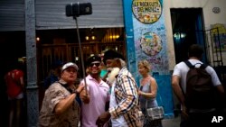 FILE - In this April 28, 2017,photo, tourists take a selfie at the Bodeguita Del Medio bar in Havana, Cuba.