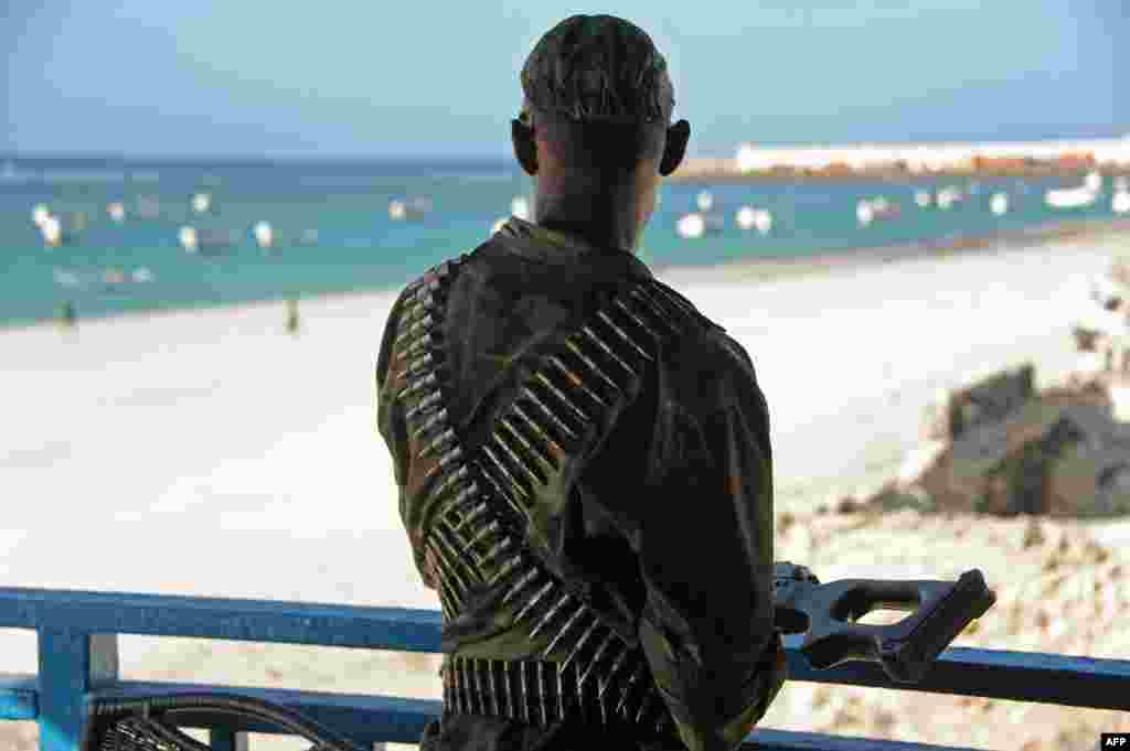 A Somali soldier looks at Lido Beach from the terrace of the Lido restaurant, following Thursday&#39;s overnight attack in Mogadishu. Islamist al-Shabab militants killed at least 19 people when five gunmen detonated a bomb before storming the popular seaside restaurant.