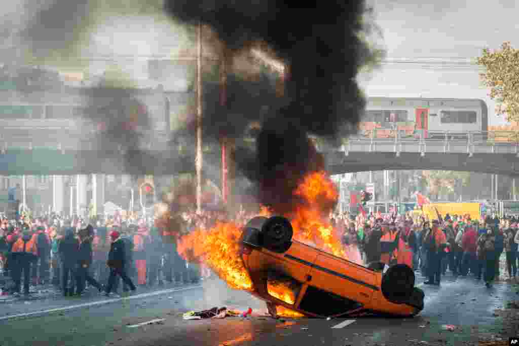 Protesters stand behind a burning car during a national trade union demonstration in Brussels, Belgium, Nov. 6, 2014.