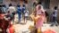 A woman receives foodstuffs including cooking oil, rice, sugar and soap, distributed by the government to families in need in the Guinaw Rails suburb of Dakar, Senegal, April 28, 2020. 