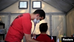 A Global Response Management worker checks the vital signs of a migrant patient at a camp where 2,000 people live while seeking asylum in the U.S., while the spread of coronavirus continues, in Matamoros, Mexico, April 9, 2020. 