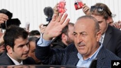 FILE - Turkish Foreign Minister Mevlut Cavusoglu, waves to supporters as he is reflected on a car after a campaign gathering in Metz, eastern France, March 12, 2017. 