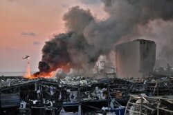 FILE - A helicopter puts out a fire at the scene of an explosion at the port of Lebanon's capital Beirut, Aug. 4, 2020.