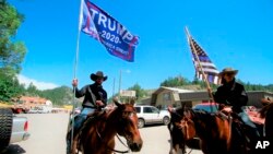 FILE - A group with Cowboys For Trump shows their support for the president in Keystone, S.D. on Friday, July 3, 2020.