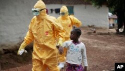 Health workers accompany a nine-year-old who contracted the Ebola virus to a Monrovia treatment center, Sept. 30, 2014.