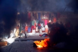 FILE - Smoke from tires set fire by protesters fills a street in Delmas where vendors sell clothing during a countrywide strike demanding the resignation of Haitian President Jovenel Moise in Port-au-Prince, Haiti, Feb. 1, 2021.