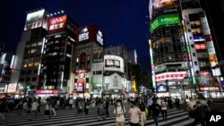 People walk along a pedestrian crossing July 30, 2021, in Tokyo.