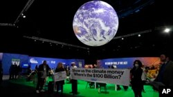 Para pengunjuk rasa memegang banner di dalam venue pada KTT Iklim COP26 U.N. di Glasgow, Skotlandia, 5 November 2021. (Foto: AP)