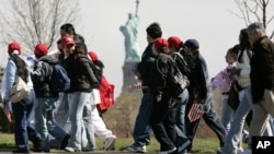 Immigrant rights supporters walk to a nearby rally with the Statue of Liberty and Ellis Island in the background, in Jersey City, New Jersey, April 2006.