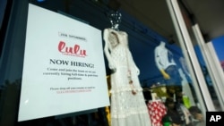 FILE - A "Now Hiring" sign is seen in a store window in the Wynwood Arts District of Miami, Florida, Jan. 27, 2021. 