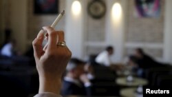 FILE - A woman holds a cigarette in a cafe in Vienna, Austria.