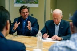 President Joe Biden listens as Florida Gov. Ron DeSantis speaks during a briefing in Miami Beach, Fla., July 1, 2021, about the collapsed condo tower in Surfside.