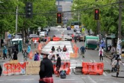 People walk past barricades on a street near Cal Anderson Park, inside what is being called the "Capitol Hill Autonomous Zone" in Seattle, June 11, 2020.