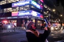 A woman wearing a protective mask takes a photo outside Times Square during the virtual New Year's Eve event following the outbreak of the coronavirus pandemic in the Manhattan borough of New York City, New York, Dec. 31, 2020.