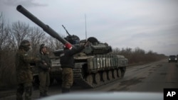 Ukrainian soldiers ask for a lift as that stand near their military vehicle near Debaltseve, eastern Ukraine, Sunday, Feb. 8, 2015.