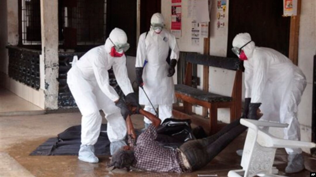 Health workers in protective gear move the body of a person that they suspect died from the Ebola virus in Monrovia, Liberia.