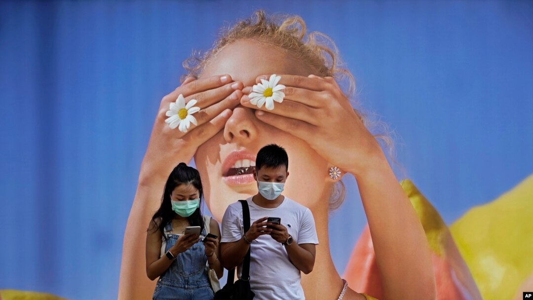 Dua orang mengenakan masker sedang mengecek ponsel mereka di Hong Kong, 27 Juli 2020.
