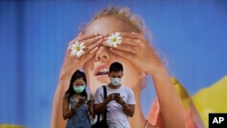 A couple wearing face masks look at their mobile phones in front of a big poster in Hong Kong, July 27, 2020.