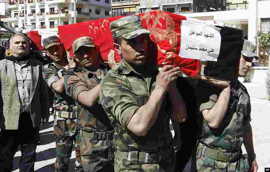Syrian military carry coffins of the victims killed in a bombing attack in Damascus, Syria. (AP)