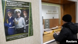 A man stands in front of a window at a district army recruiting office in Kiev March 2, 2014.