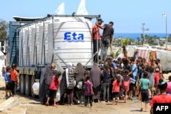 Orang-orang berkumpul untuk mengisi wadah air mereka dari truk yang memuat tangki air di Rafah di Jalur Gaza selatan pada 25 Juni 2024 di tengah konflik yang sedang berlangsung di wilayah Palestina antara Israel dan Hamas. (Foto: AFP)