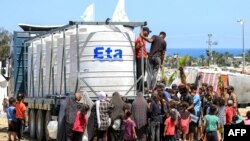 Un grupo de personas se reúnen para llenar sus bidones de agua desde un camión cargado con cisternas en Rafah, en el sur de la Franja de Gaza, el 25 de junio de 2024, en medio del conflicto en curso en el territorio palestino entre Israel y Hamás.