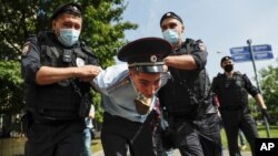 Police officers detains a protester, center, dressed as a Russian police officer before a court hearing of the New Greatness group who are charged with the organization of an extremist association in Moscow, Russia, Aug. 6, 2020.