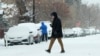 A pedestrian crosses First Avenue as a winter storm sweeps over the intermountain West, plunging temperatures into the single digits and bringing along a light snow in its wake, Jan. 18, 2025, in Denver.