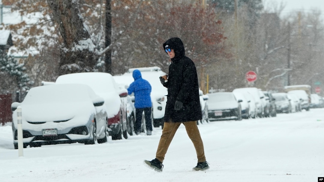 A pedestrian crosses First Avenue as a winter storm sweeps over the intermountain West, plunging temperatures into the single digits and bringing along a light snow in its wake, Jan. 18, 2025, in Denver.