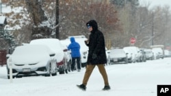 A pedestrian crosses First Avenue as a winter storm sweeps over the intermountain West, plunging temperatures into the single digits and bringing along a light snow in its wake, Jan. 18, 2025, in Denver.