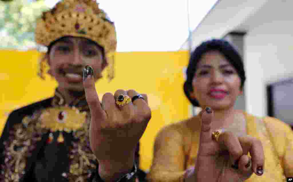 Seorang pengantin pria Bali dan ibunya menunjukkan jari yang sudah ditandai tinta setelah mencoblos di sebuah TPS di Bali, 17 April 2019. (Foto: Frida Lisnawati/AP)