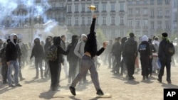 A young man throws a bottle against anti riot police, 21 October 2010, during clashes in Lyon, southern France, during a demonstration to protest against the pensions reform.