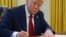 (FILE) President Donald Trump signs a document in the Oval Office at the White House, Jan. 30, 2025, in Washington. 