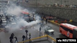 Riot police try to disperse protesters as they rally on a highway against increased fuel prices, in Tehran, Iran, Nov. 16, 2019.