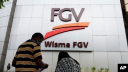 A couple talks outside FGV Holdings Berhad, one of Malaysia's largest palm oil companies, in Kuala Lumpur, Oct. 1, 2020. 