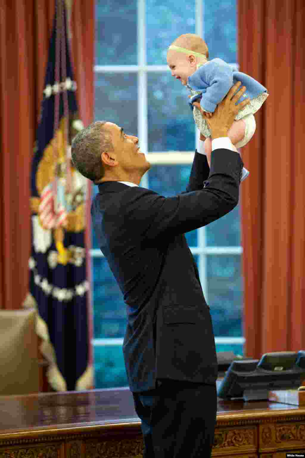 U.S. President Barack Obama lifts the daughter of a departing staff member in the Oval Office, Oct. 14, 2014. (Official White House Photo by Pete Souza)