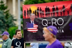 Romanian supporters of QAnon take part in a rally against the government's measures to prevent the spread of COVID-19 infections, like wearing a face mask, in Bucharest, Romania, Aug. 10, 2020.