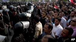 Supporters of Egyptian President Mohammed Morsi chant slogans as riot police, left, stand guard in front of the entrance of Egypt’s top court, in Cairo, Egypt, Sunday, Dec. 2, 2012.