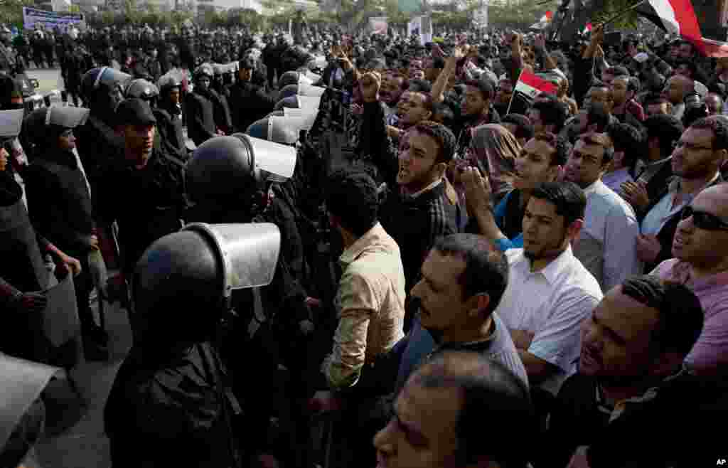 Supporters of Egyptian President Mohammed Morsi chant slogans as riot police, left, stand guard in front of the entrance of Egypt’s top court, in Cairo, Egypt, Sunday, Dec. 2, 2012.