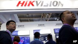 Para pengunjung melintas di depan stan produsen peralatan pengintaian China, Hikvision, di sebuah pameran di Beijing, China, 23 Oktober 2018. (Foto: AP/Ng Han Guan). 